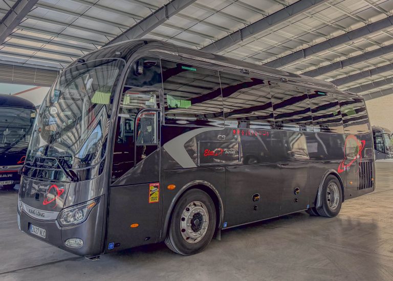 Black King Long Elite Touring tour bus in a showroom, angled front-right view showing glossy exterior and large windshield.