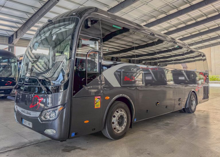 Black luxury motorhome inside a showroom, front cab visible with large curved windshield and side mirrors.