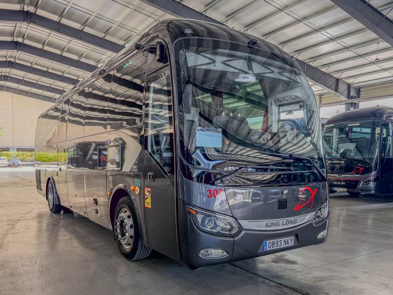 Front three-quarter view of a glossy black King Long coach inside a showroom, license plate 0893 NKY visible on the bumper